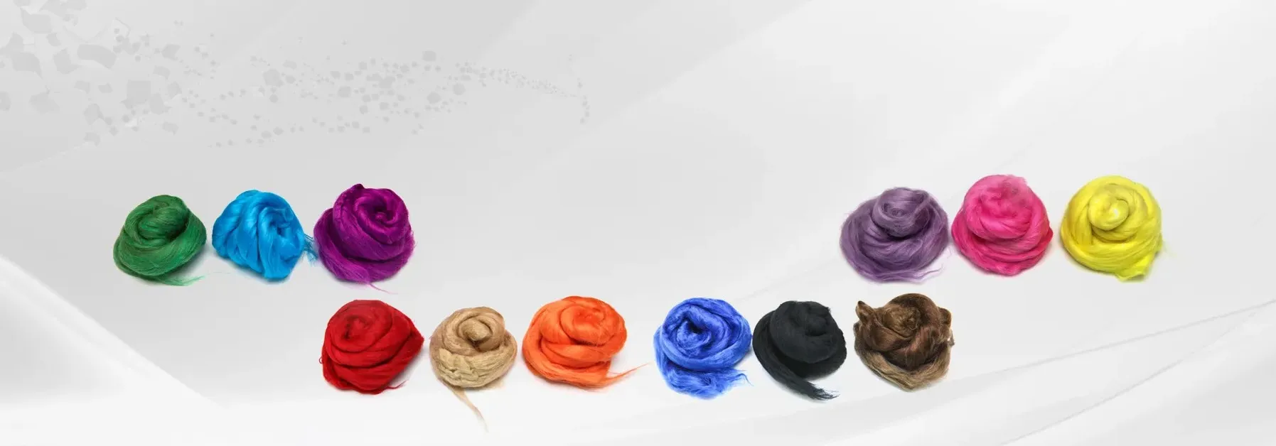 Various colored dyed tops arranged in rows on a white surface, showing different vibrant colors including green, blue, purple, red, beige, orange, royal blue, black, brown, lavender, pink, and yellow